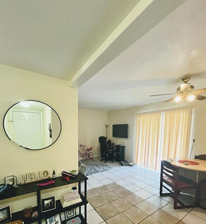 A living area with tile floors, a ceiling fan, a dining table, and a wall mirror — 5885 DAHLIA DRIVE UNIT 29/115, ORLANDO, FL