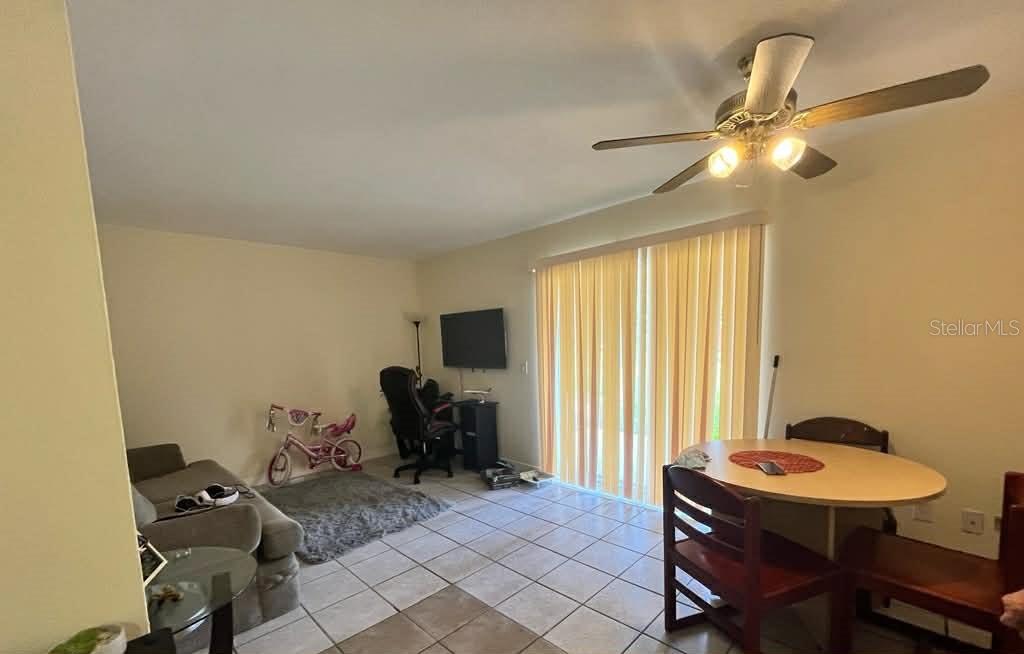 A living and dining area with tile flooring, a ceiling fan, and sliding glass doors — 5885 DAHLIA DRIVE UNIT 29/115, ORLANDO, FL