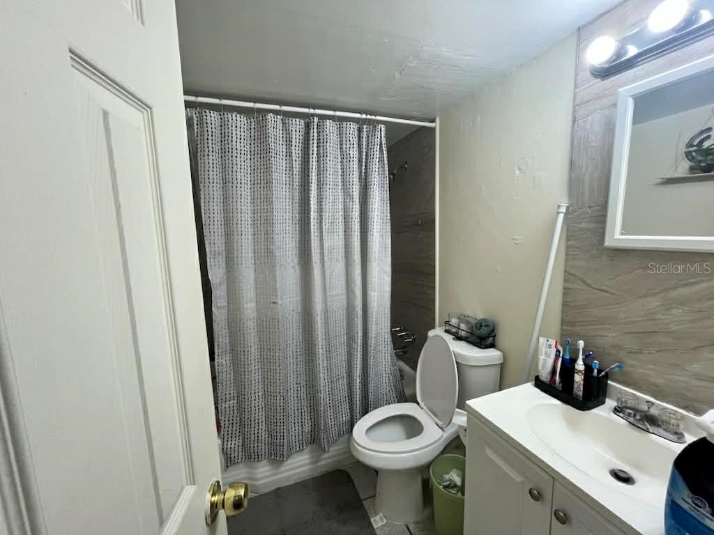 A bathroom features a white vanity, a toilet, and a shower with a patterned curtain — 5885 DAHLIA DRIVE UNIT 29/115, ORLANDO, FL
