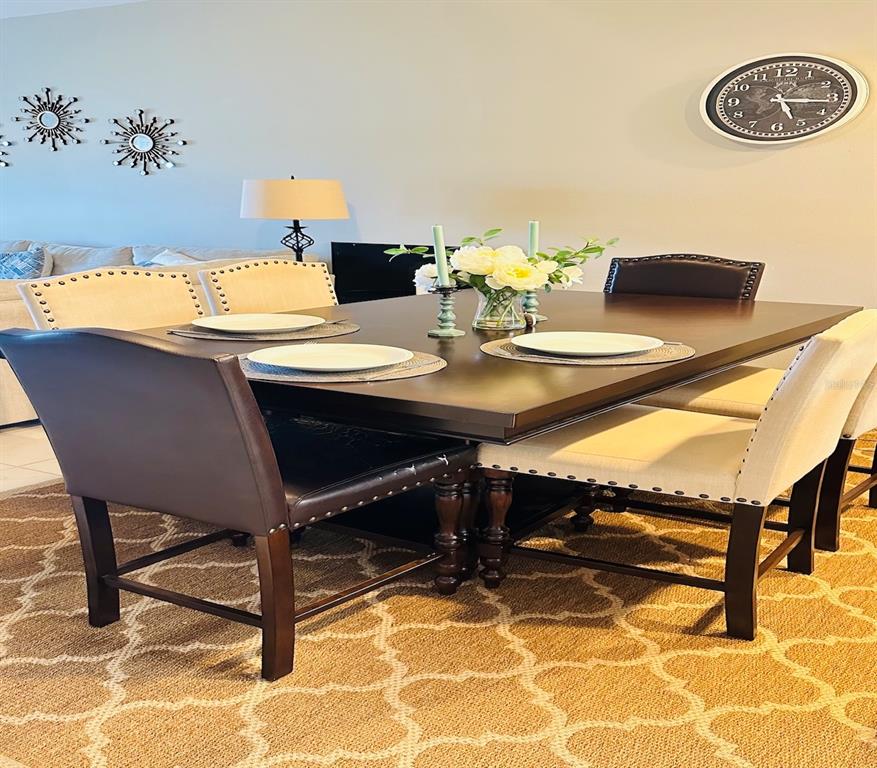 A dining room features a dark wood table, upholstered chairs, and a wall clock — 1852 77TH DRIVE, VERO BEACH, FL