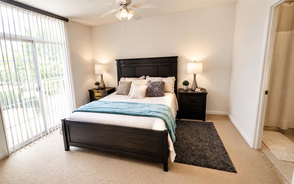 A bedroom features a dark wood bed frame, two matching nightstands, and a sliding glass door — 1852 77TH DRIVE, VERO BEACH, FL