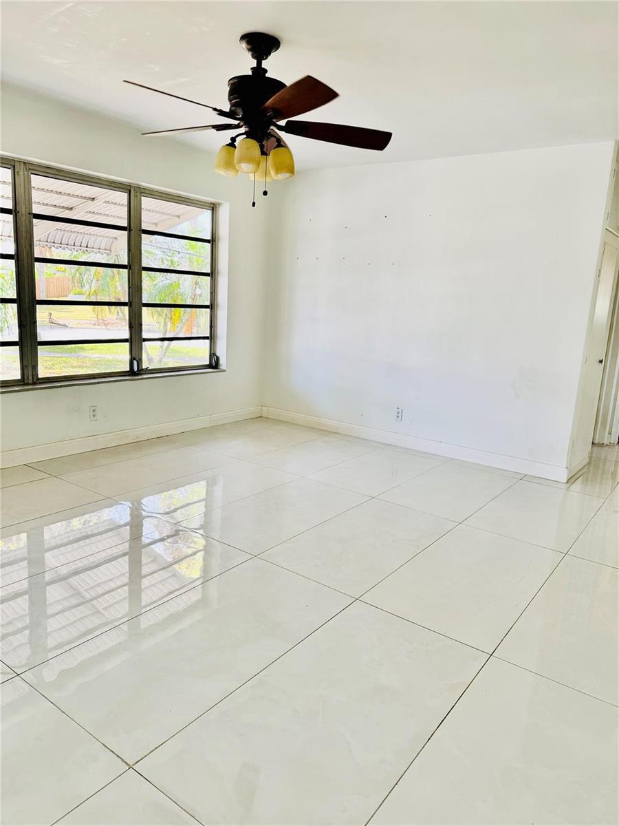 A bright room with white tile floors, a ceiling fan, and large windows — 1521 NW 62nd Terrace, Margate FL 33063, MARGATE, FL