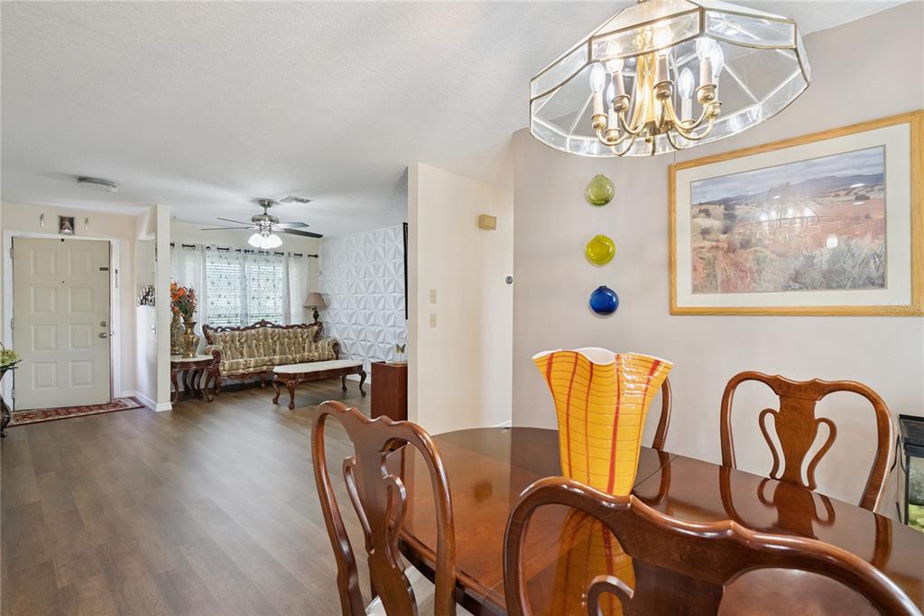 A dining area with a wooden table and chandelier opens into a living room space — 1405 CORONET DRIVE, DELTONA, FL