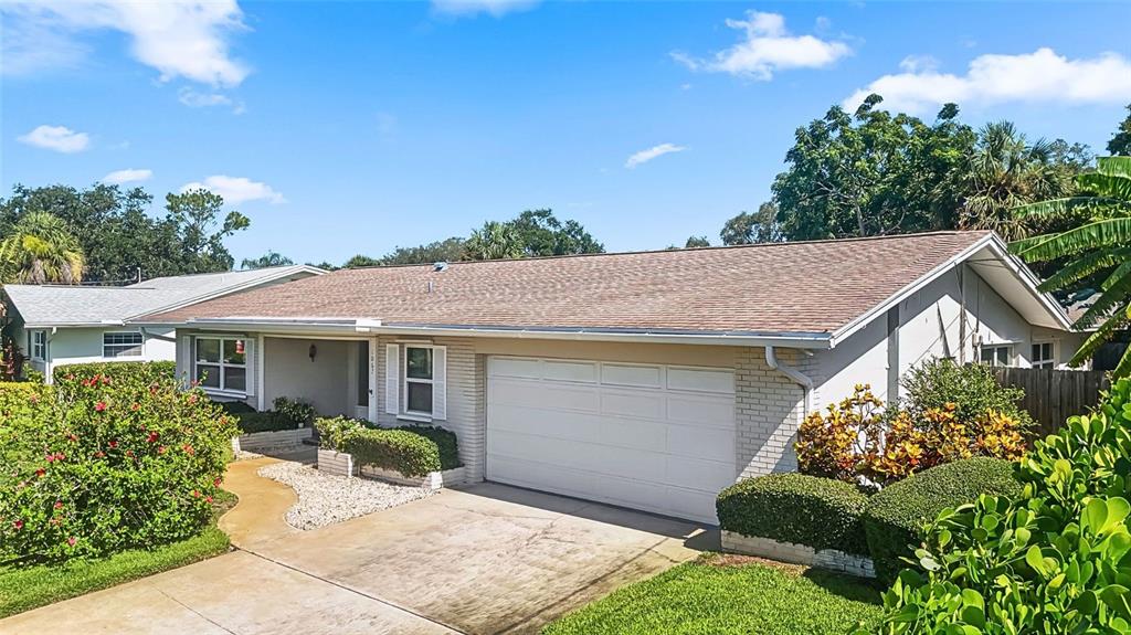 A single-story house with a light-colored brick facade, a two-car garage, and a shingled roof — 1067 44TH AVENUE NE, ST PETERSBURG, FL