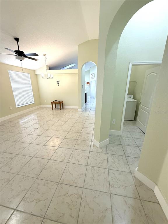 A tiled living area features a ceiling fan, arched doorways, and a view into a laundry room — 4207 ANDOVER CAY BOULEVARD, ORLANDO, FL