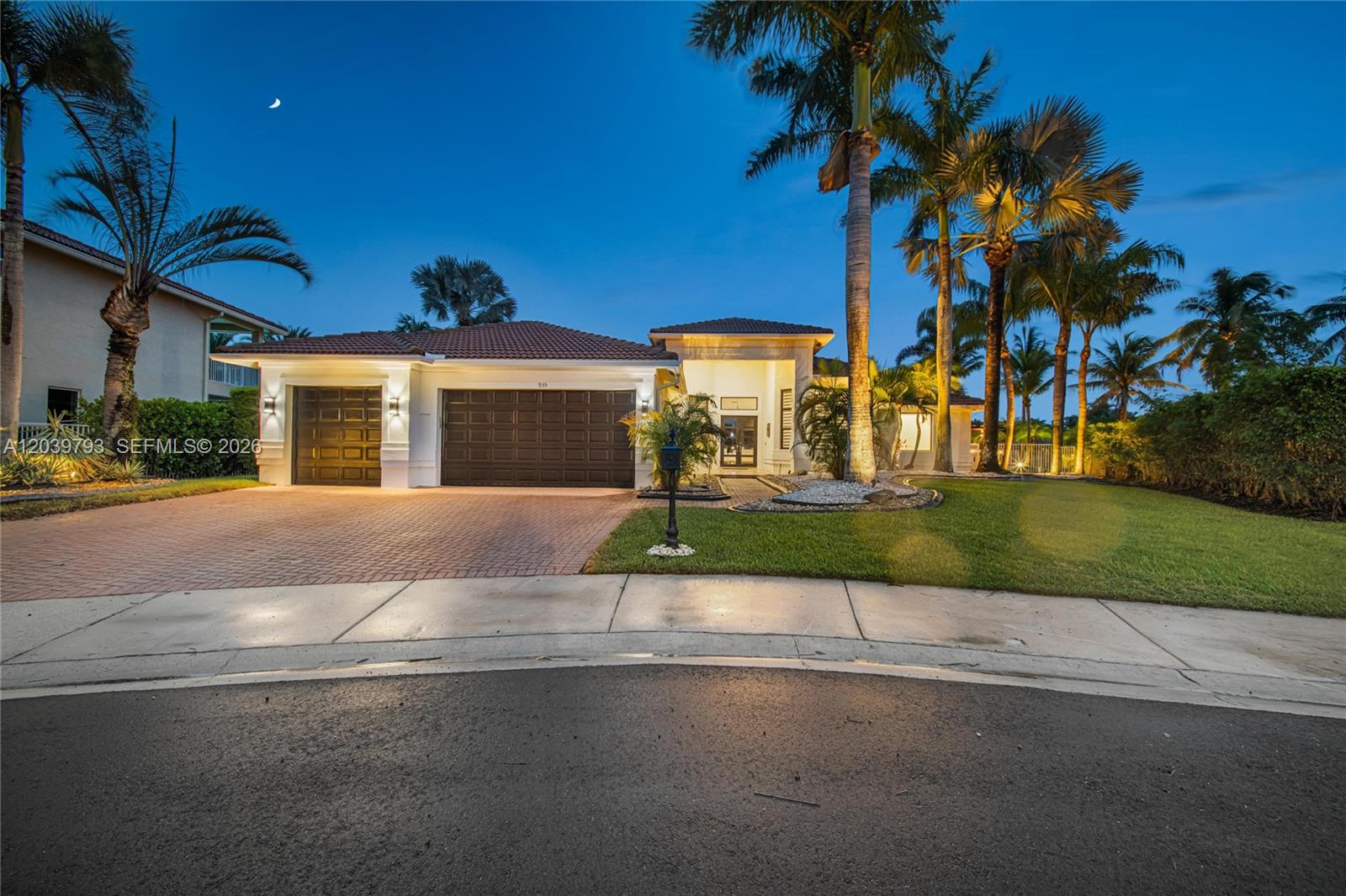 A single-story house with a three-car garage and palm trees at twilight — 935 Gulfstream Ct, Weston FL 33327, WESTON, FL