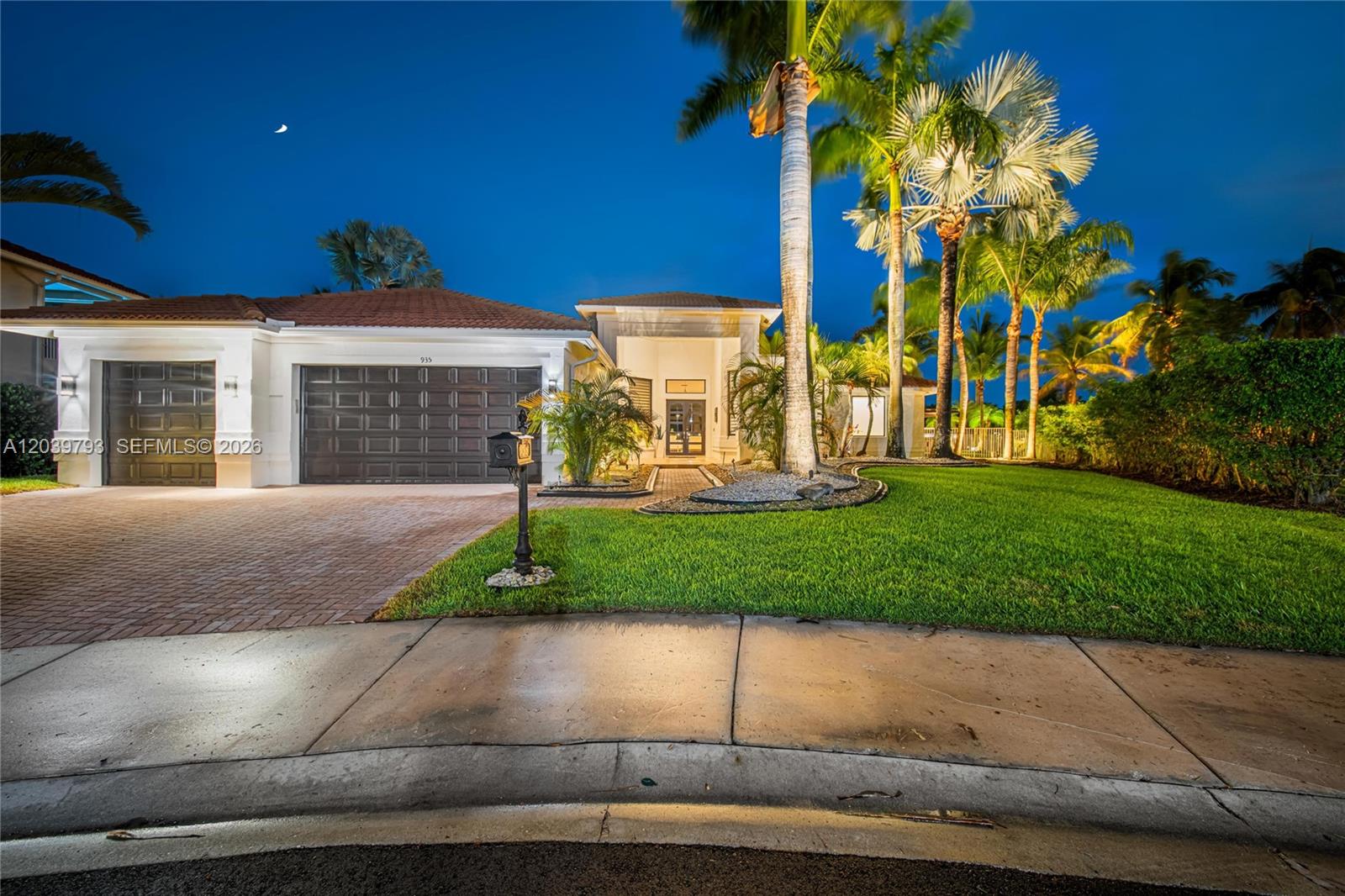 A single-story house with a brick driveway, dark garage doors, and palm trees at night — 935 Gulfstream Ct, Weston FL 33327, WESTON, FL