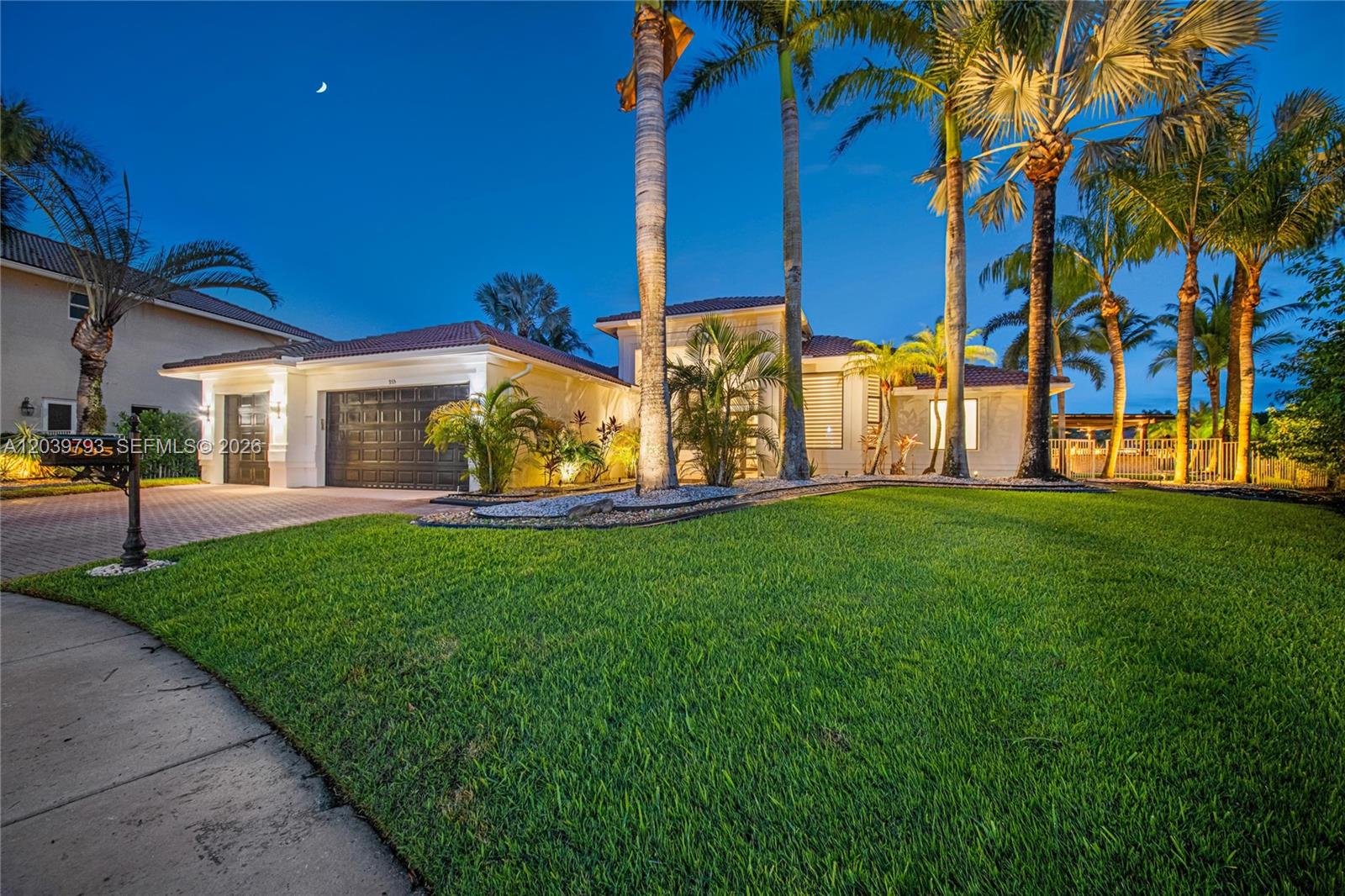 A single-story house with a two-car garage and palm trees at dusk — 935 Gulfstream Ct, Weston FL 33327, WESTON, FL