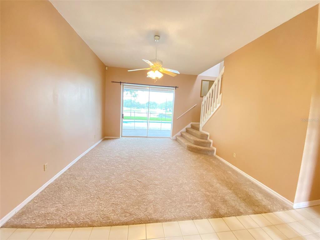 A living room features beige carpet, tan walls, a ceiling fan, and stairs with railings — 3708 MOLONA DRIVE, ORLANDO, FL