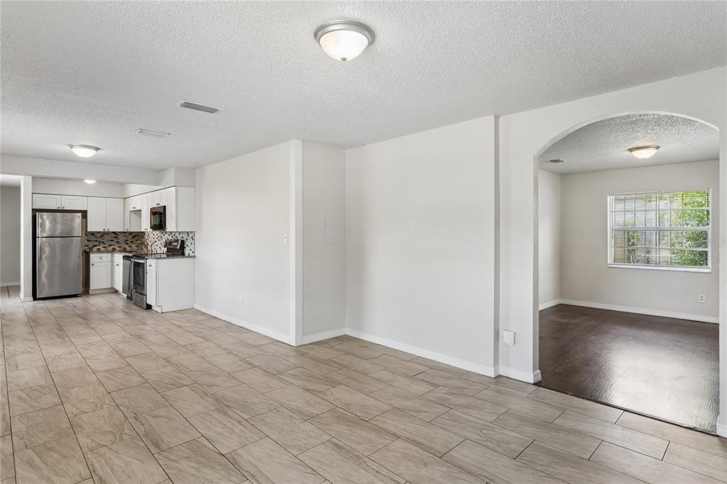 A kitchen with stainless steel appliances and tile flooring opens to a dining area — 9608 N 10TH STREET, TAMPA, FL