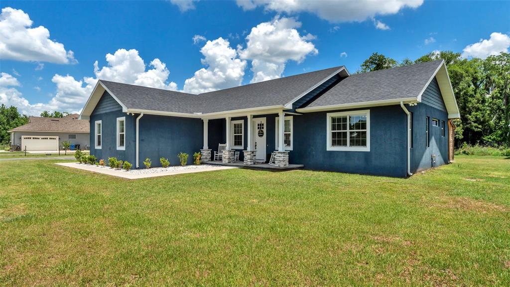 A blue single-story house with a white-trimmed front porch and a grassy yard — 3111 BELL BEGINNINGS COURT, PLANT CITY, FL