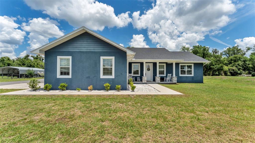 A blue, single-story house with a covered front porch and white trim sits on grass — 3111 BELL BEGINNINGS COURT, PLANT CITY, FL