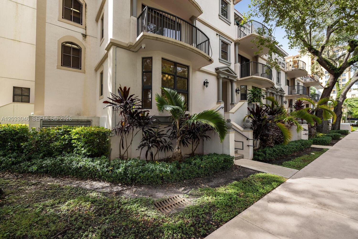 A multi-story residential building exterior features balconies, arched windows, and landscaped gardens along a sidewalk — 1650 Galiano St, Coral Gables FL 33134, CORAL GABLES, FL