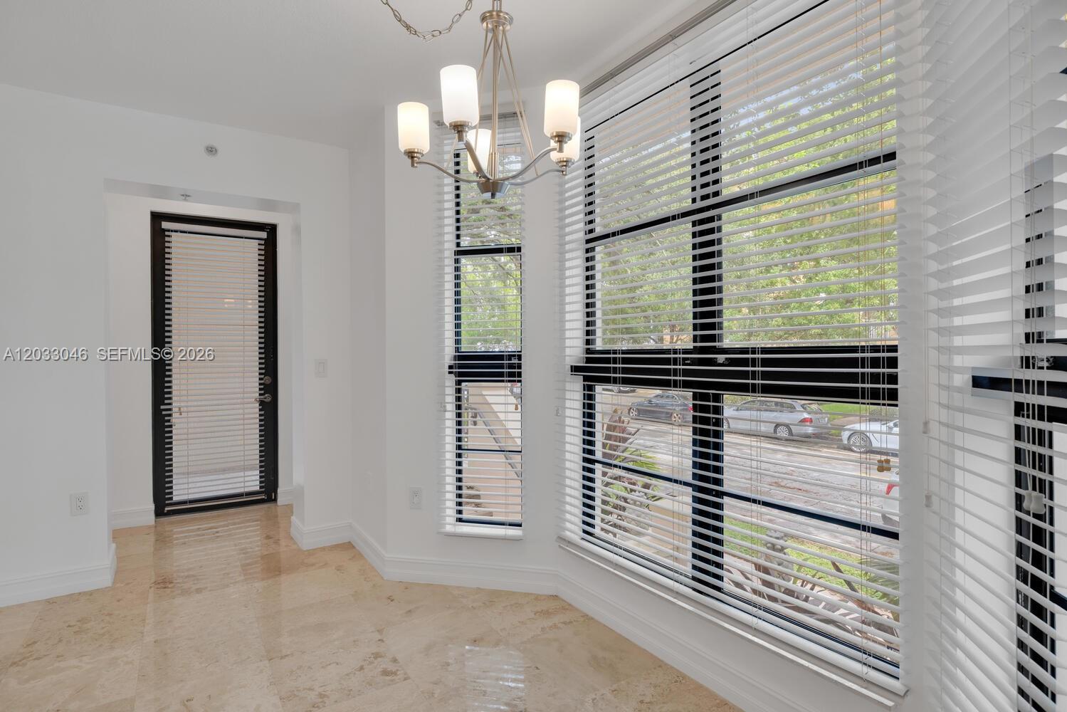 A dining area features a chandelier, large windows with blinds, and light-colored tile flooring — 1650 Galiano St, Coral Gables FL 33134, CORAL GABLES, FL