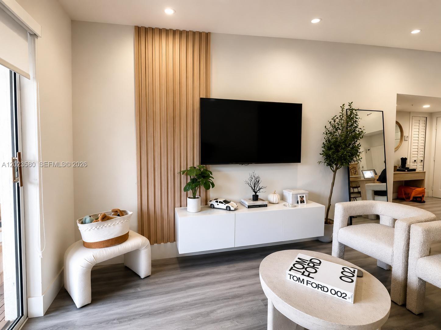 A living room features a wall-mounted television, wood slat paneling, and a floating white console — 4420 NW 107th Ave # 303, Doral FL 33178, DORAL, FL