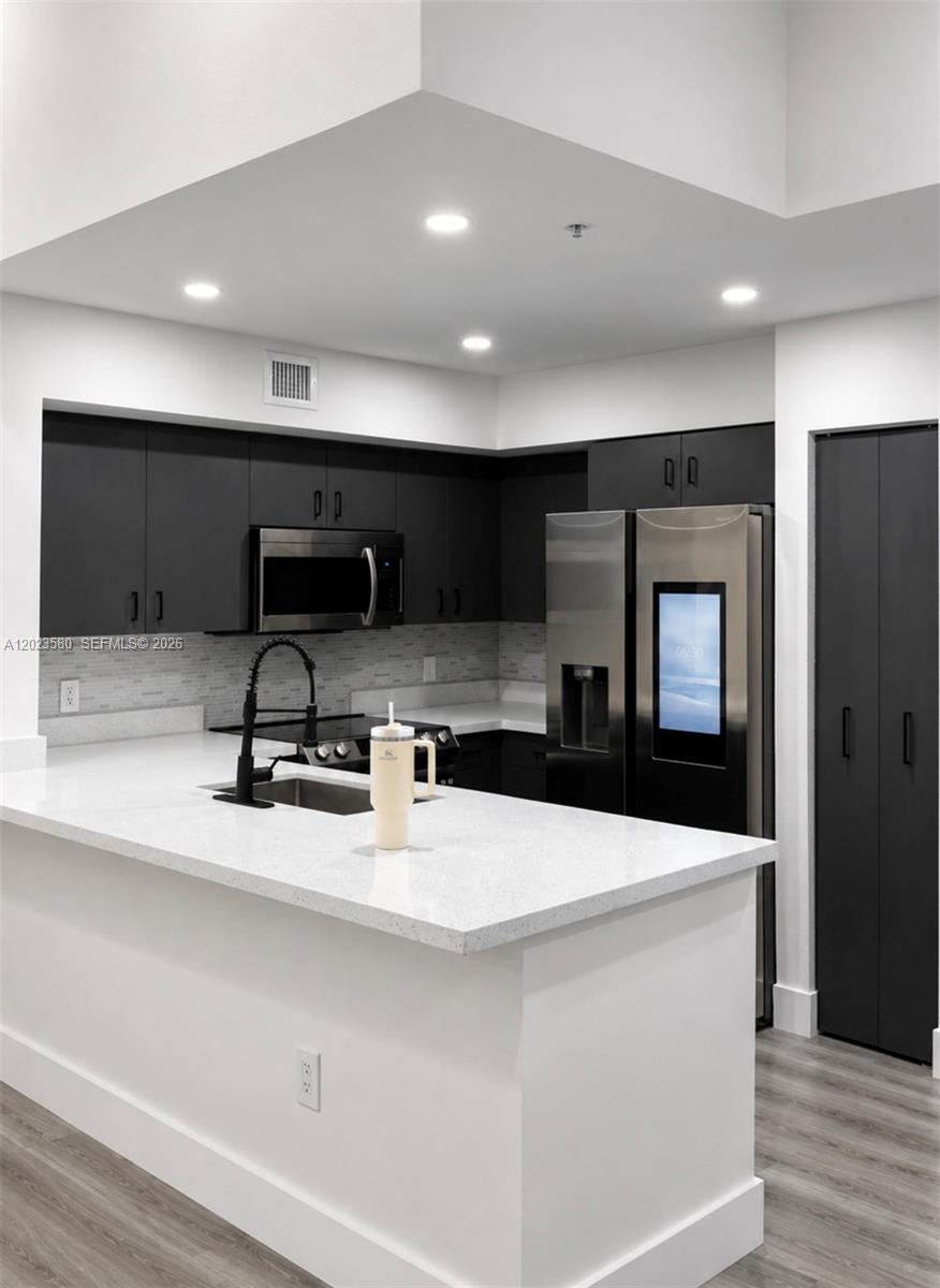 A modern kitchen features dark cabinetry, stainless steel appliances, and a white quartz countertop island — 4420 NW 107th Ave # 303, Doral FL 33178, DORAL, FL