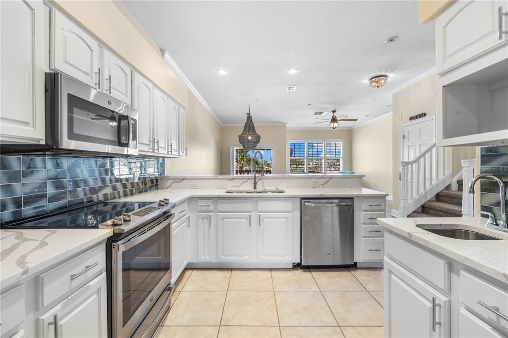 A kitchen with white cabinets, stainless steel appliances, and a tiled floor — 116 131ST AVENUE E UNIT F, MADEIRA BEACH, FL