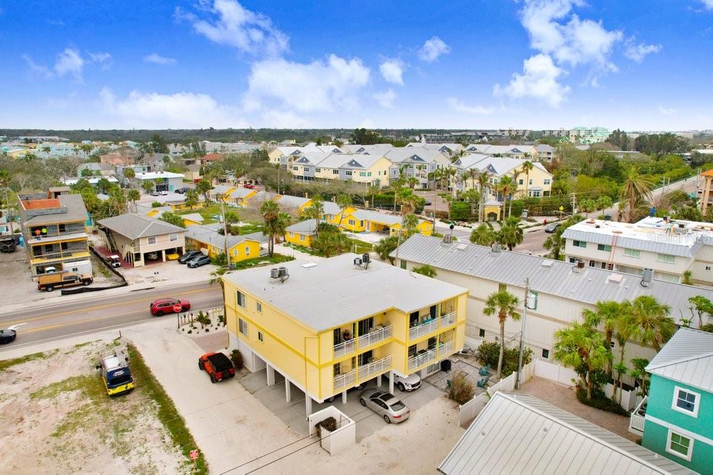 An aerial view shows a yellow multi-story apartment building with balconies and surrounding residential properties — 708 GULF BOULEVARD UNIT A, INDIAN ROCKS BEACH, FL