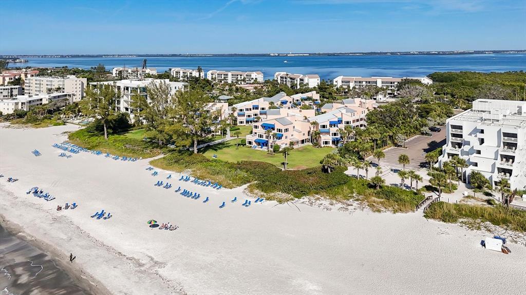An aerial view shows a beach resort with multi-story buildings, a sandy shore, and ocean — 4725 GULF OF MEXICO DRIVE UNIT 314, LONGBOAT KEY, FL