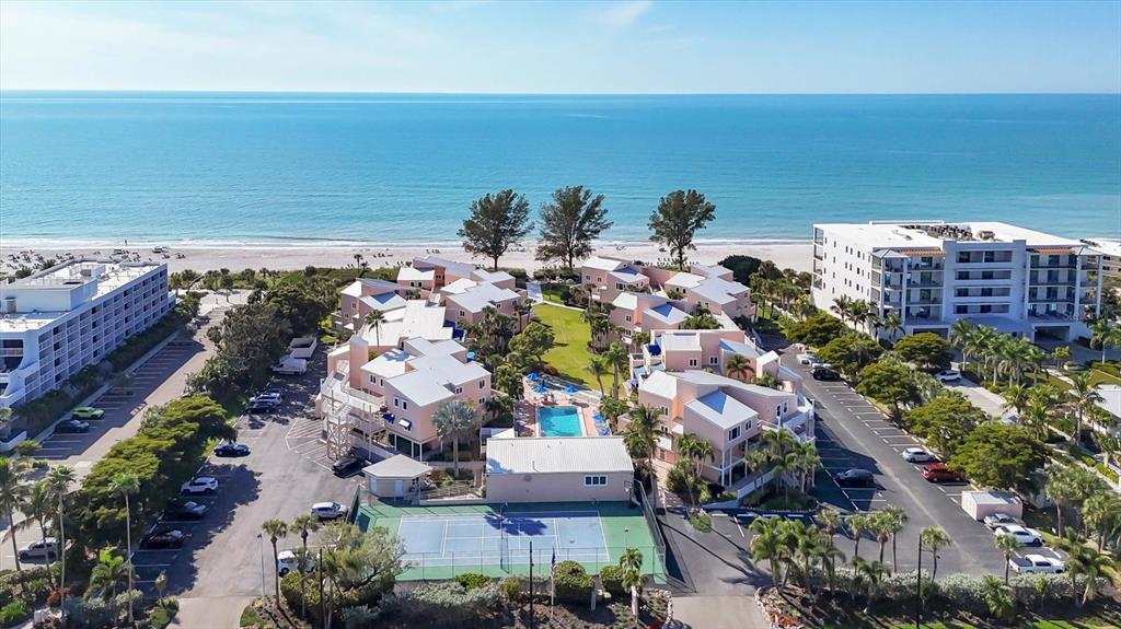 An aerial view shows a beachfront resort complex with a tennis court and swimming pool — 4725 GULF OF MEXICO DRIVE UNIT 314, LONGBOAT KEY, FL