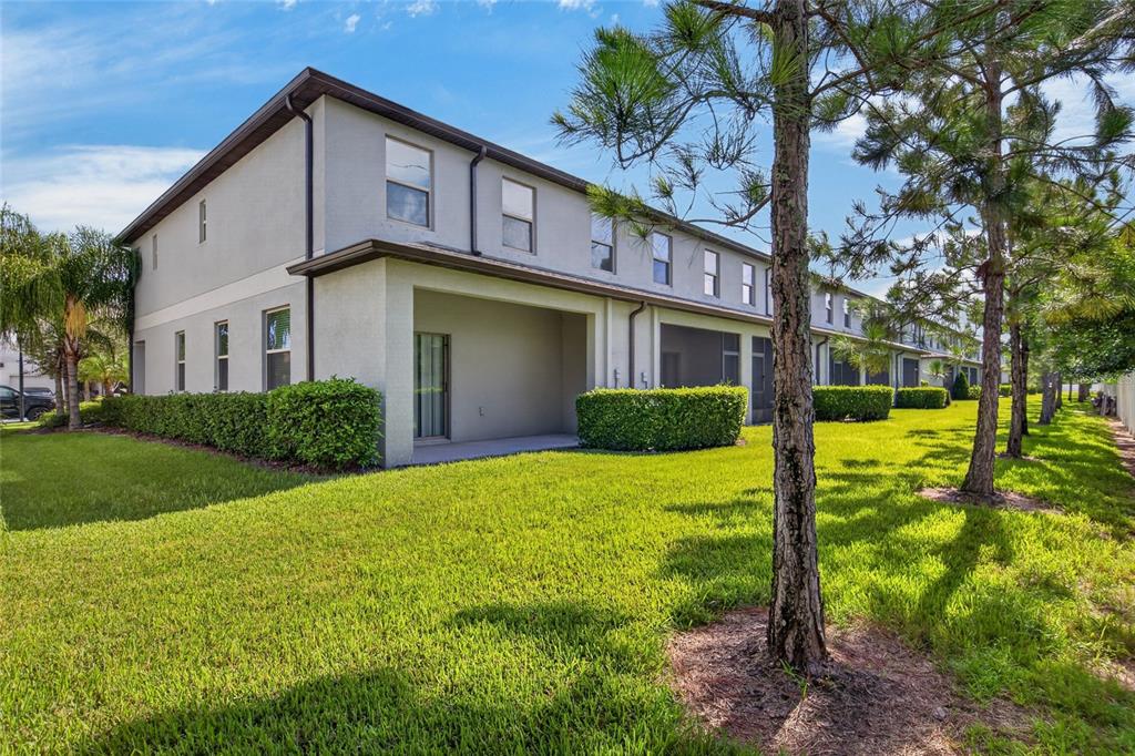 The exterior of a two-story townhouse featuring a covered patio and a grassy backyard — 7617 GINGER LILY COURT, TAMPA, FL
