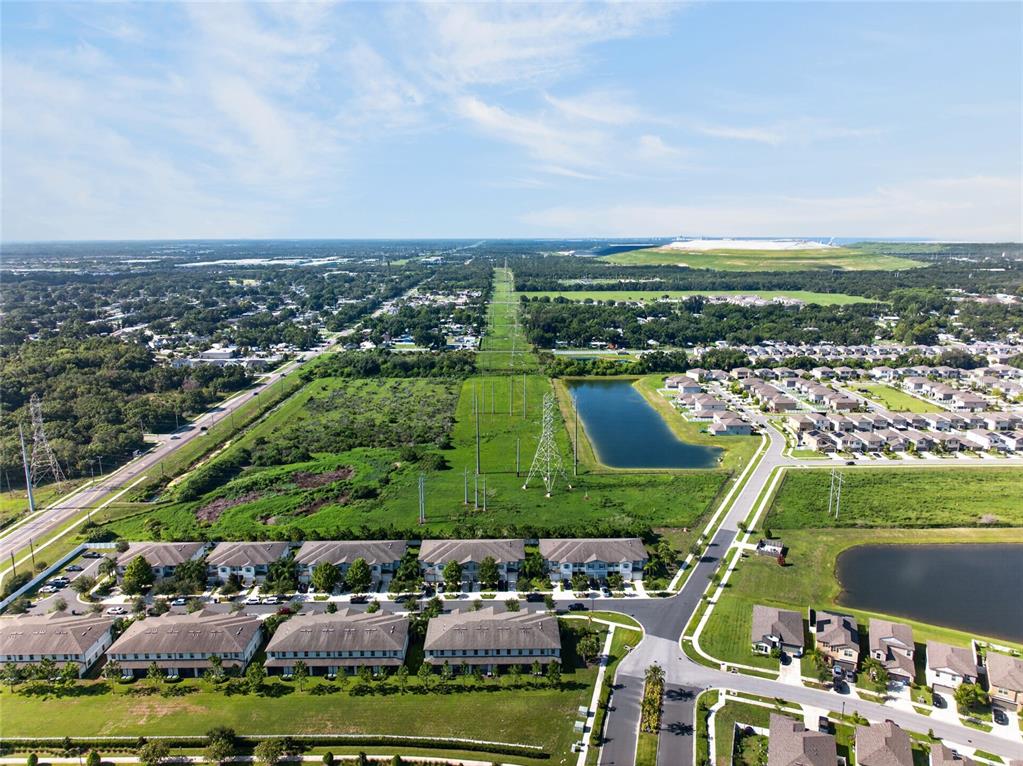 An aerial view shows a suburban neighborhood with townhomes, a retention pond, and power lines — 7617 GINGER LILY COURT, TAMPA, FL
