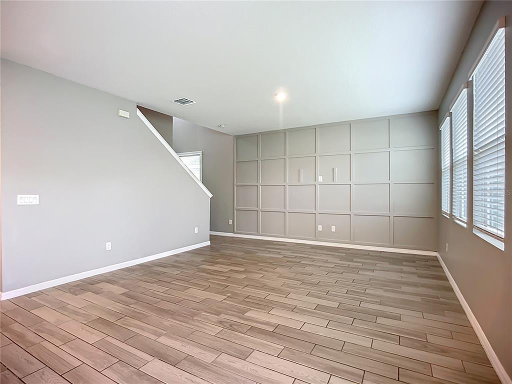 An empty room features wood-look tile flooring, gray walls, and a paneled accent wall — 11829 CLARE HILL AVENUE, RIVERVIEW, FL