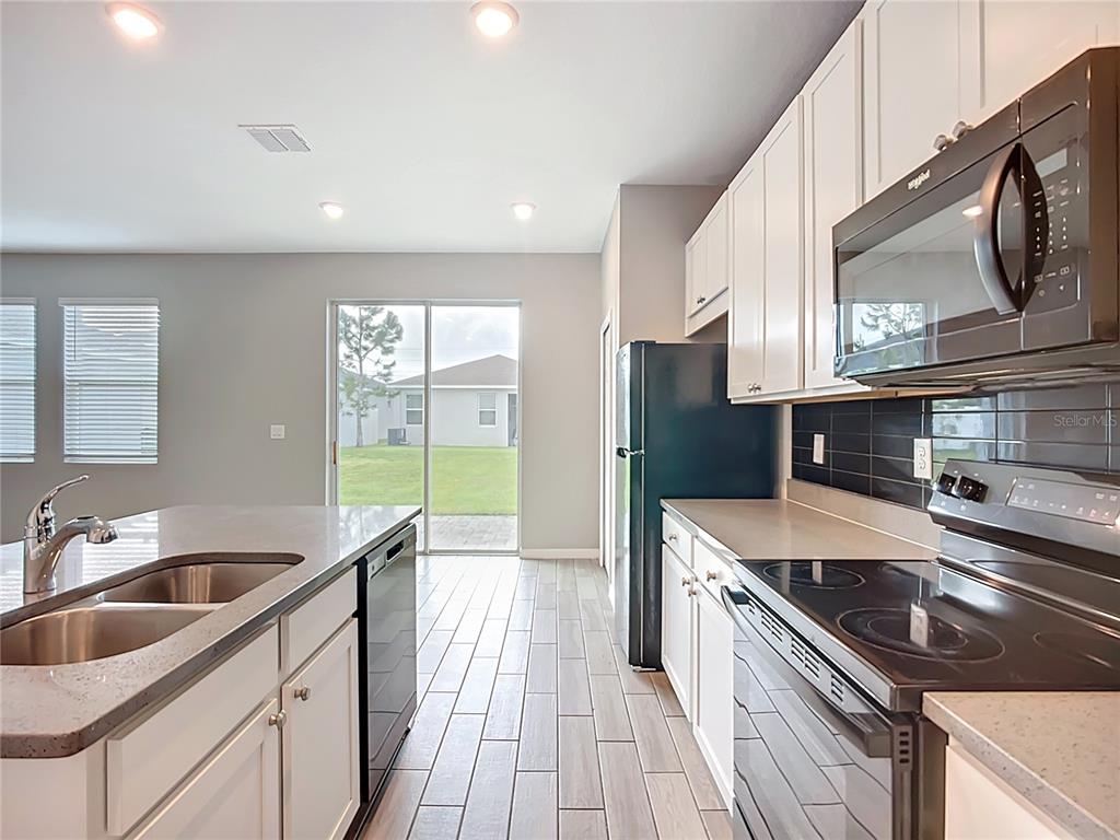 A kitchen features white cabinets, stainless steel appliances, a center island, and tile flooring — 11829 CLARE HILL AVENUE, RIVERVIEW, FL