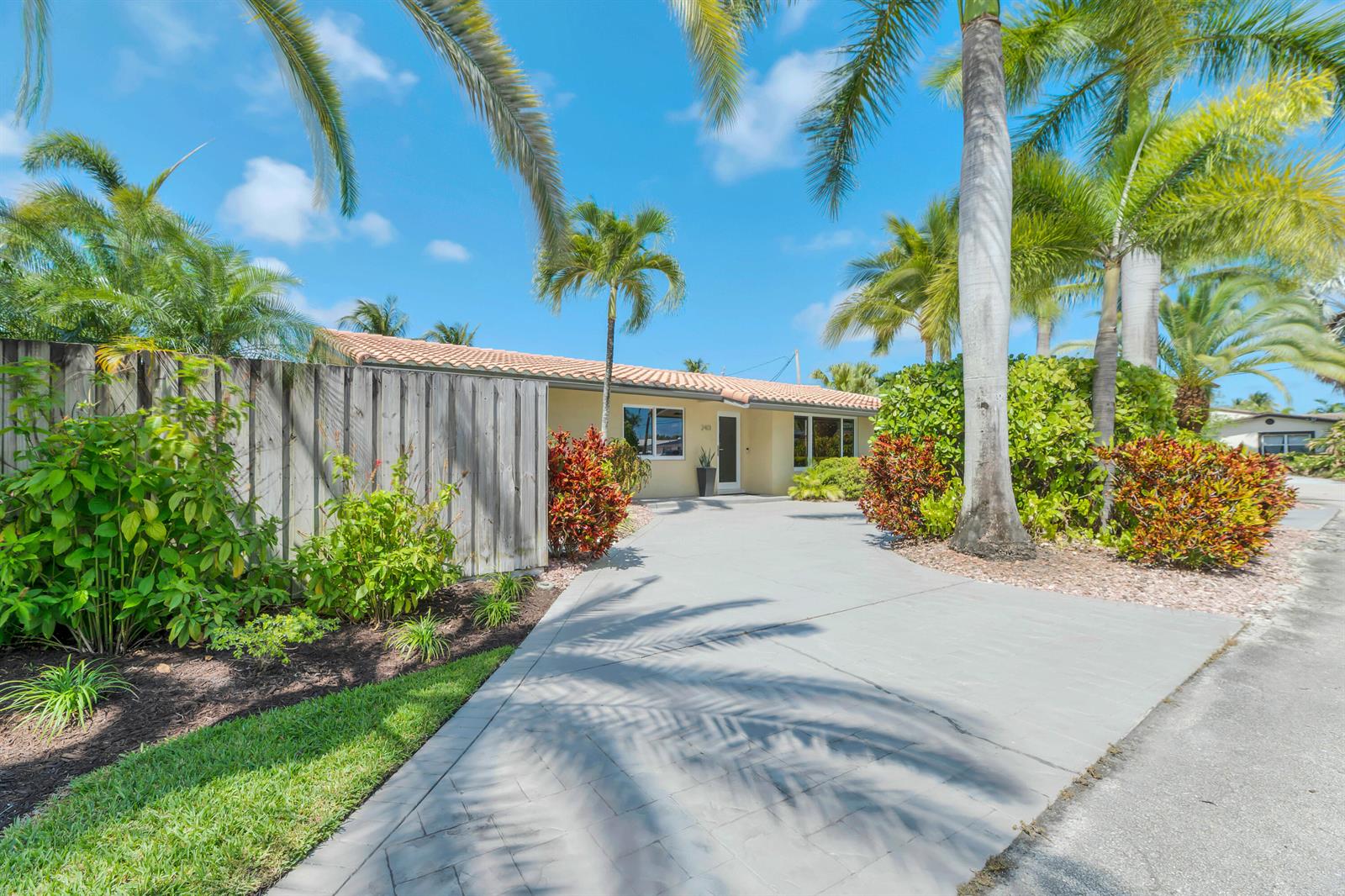A single-story house with a tiled roof, concrete driveway, and palm trees in the yard — 2401 NE 17th Terrace, Wilton Manors FL 33305, WILTON MANORS, FL