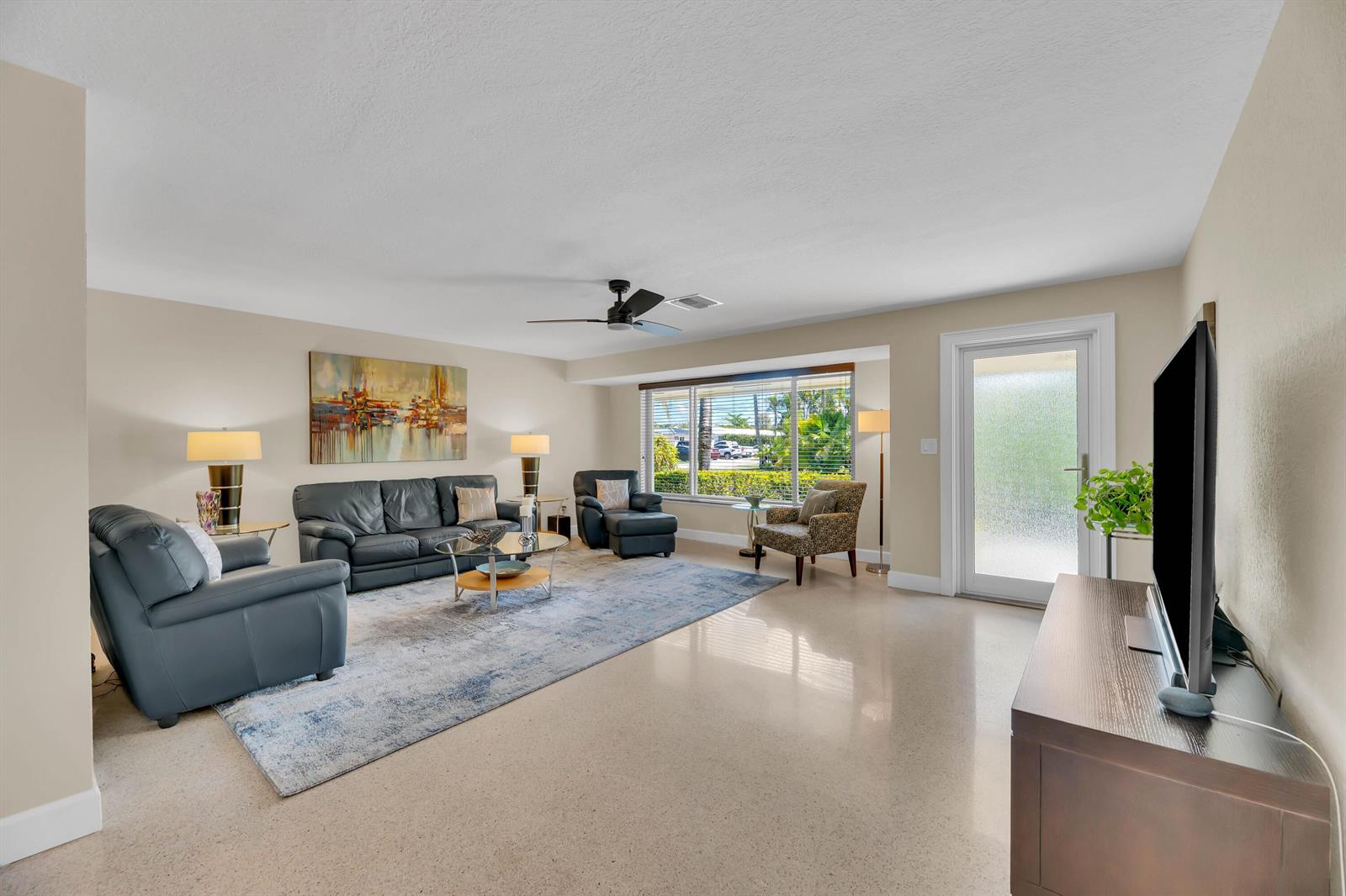 A living room features a leather sofa set, a patterned area rug, and a glass door — 2401 NE 17th Terrace, Wilton Manors FL 33305, WILTON MANORS, FL