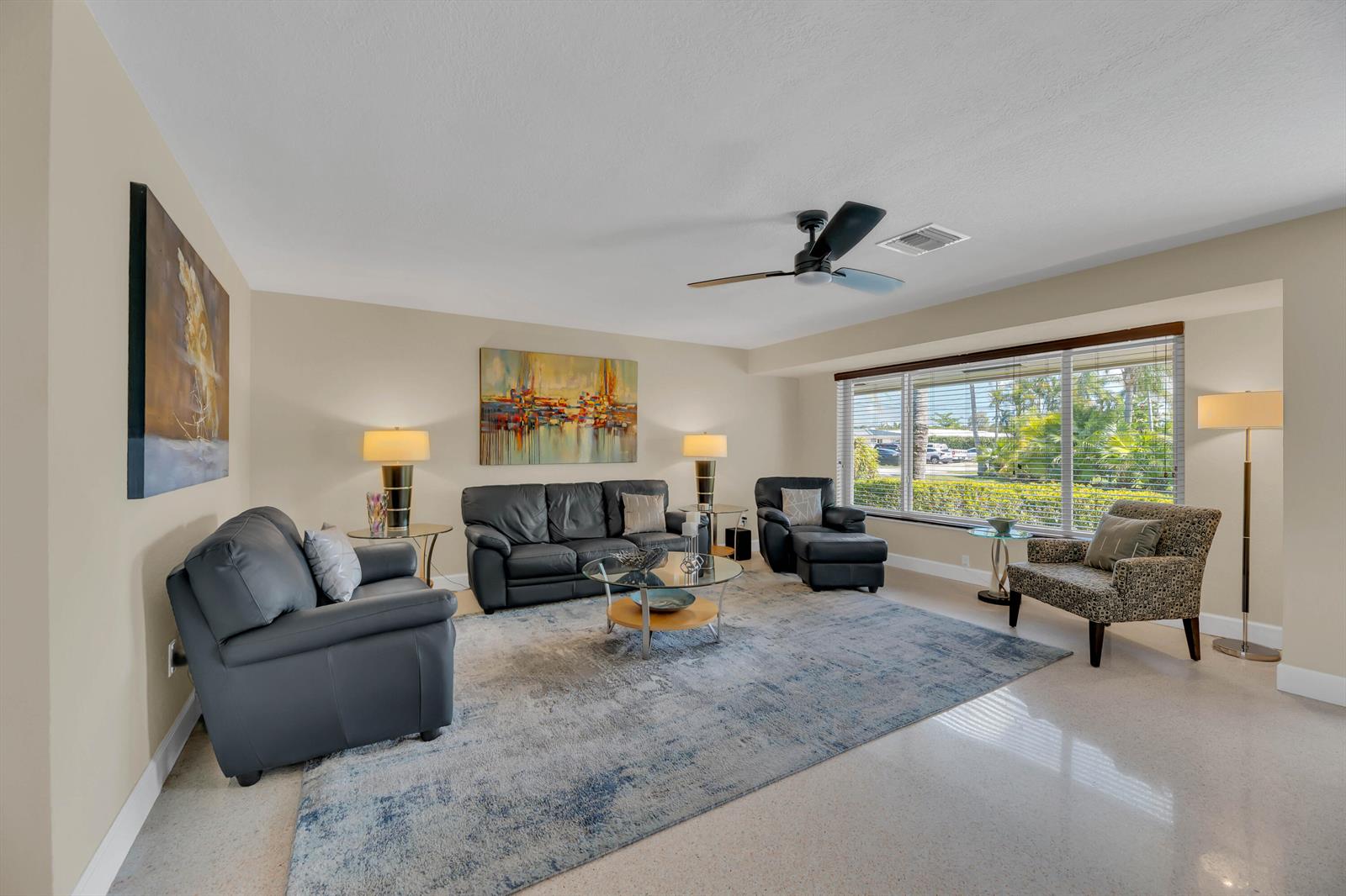 A living room features leather sofas, a patterned armchair, a large area rug, and windows — 2401 NE 17th Terrace, Wilton Manors FL 33305, WILTON MANORS, FL