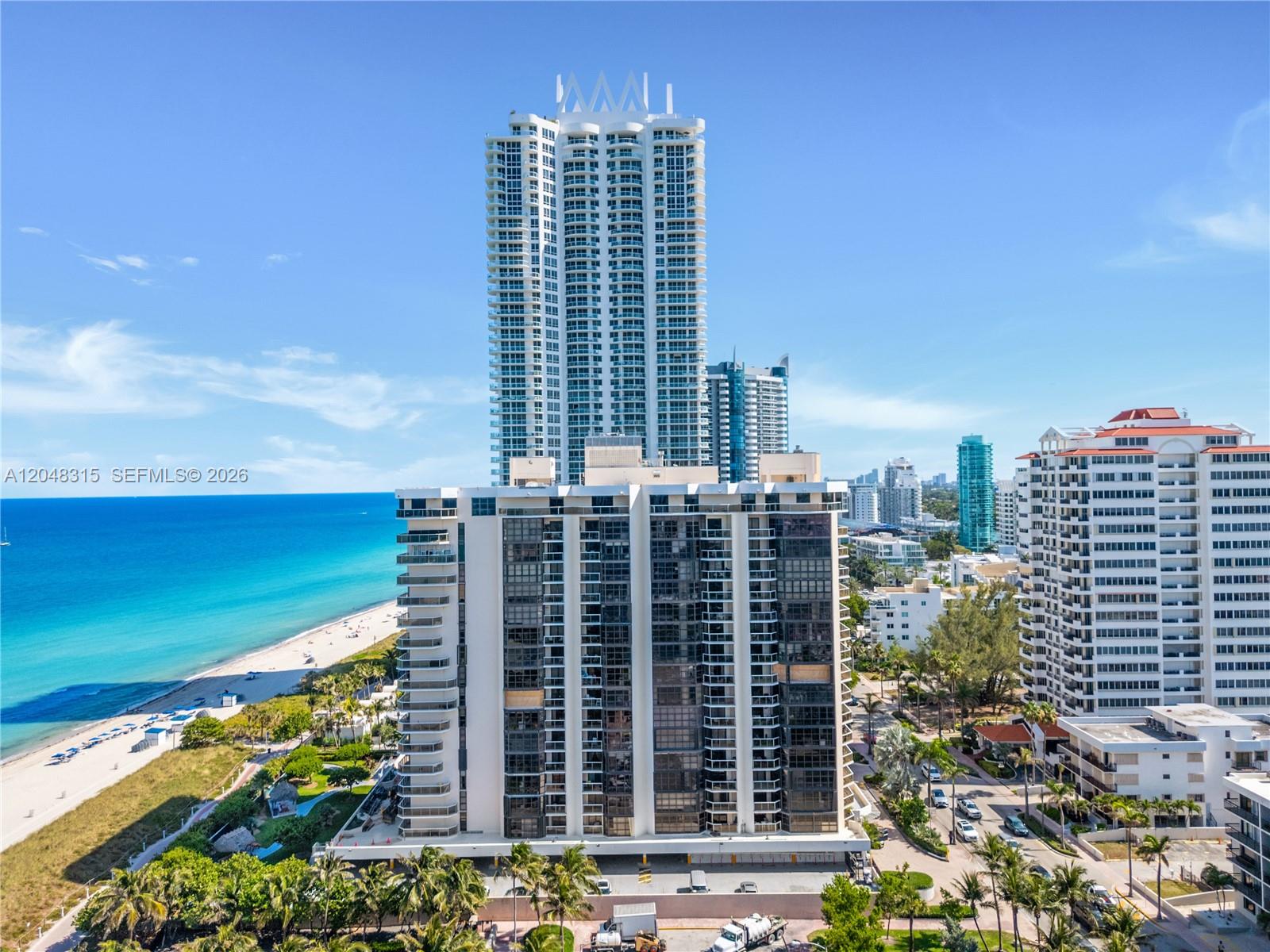 An aerial view shows high-rise apartment buildings situated along a sandy beach and ocean — 6423 Collins Ave # 703, Miami Beach FL 33141, MIAMI BEACH, FL