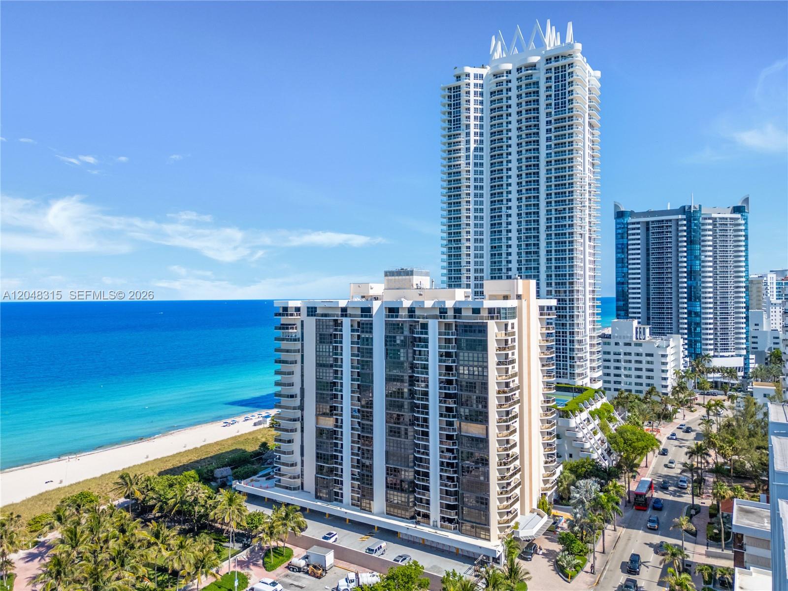 An aerial view shows high-rise residential buildings situated along a sandy beach and ocean — 6423 Collins Ave # 703, Miami Beach FL 33141, MIAMI BEACH, FL