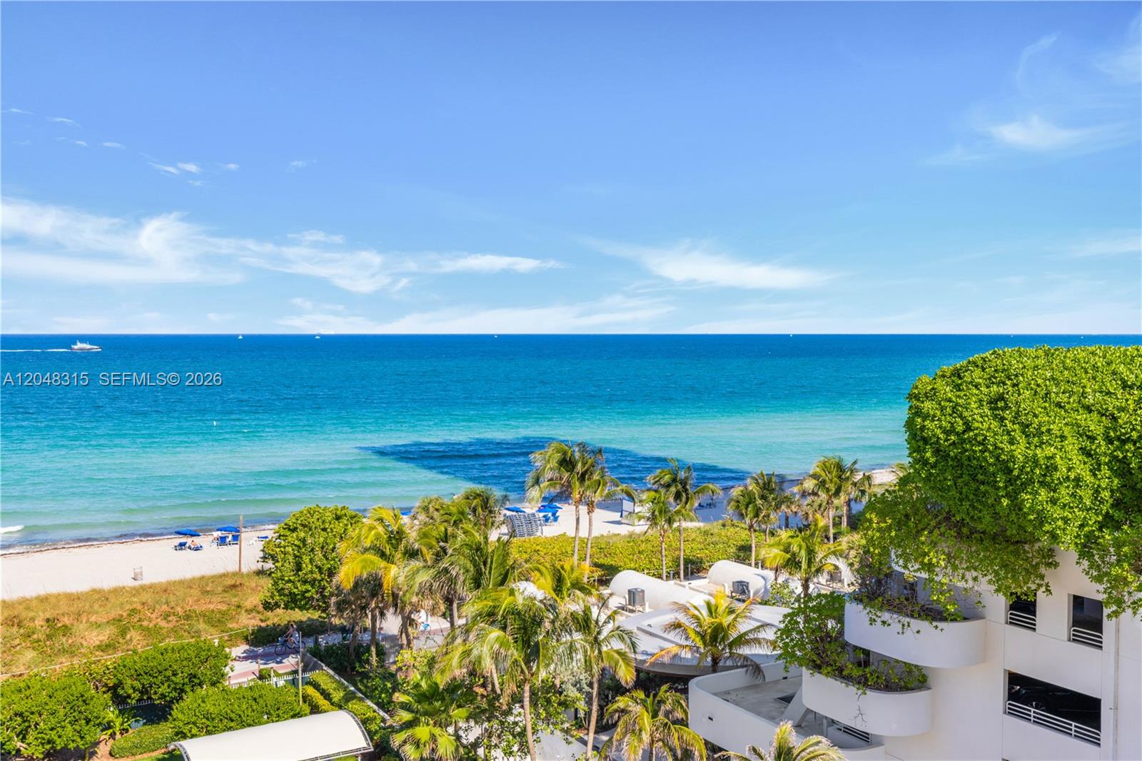 An elevated view shows a sandy beach, palm trees, and the ocean under a blue sky — 6423 Collins Ave # 703, Miami Beach FL 33141, MIAMI BEACH, FL