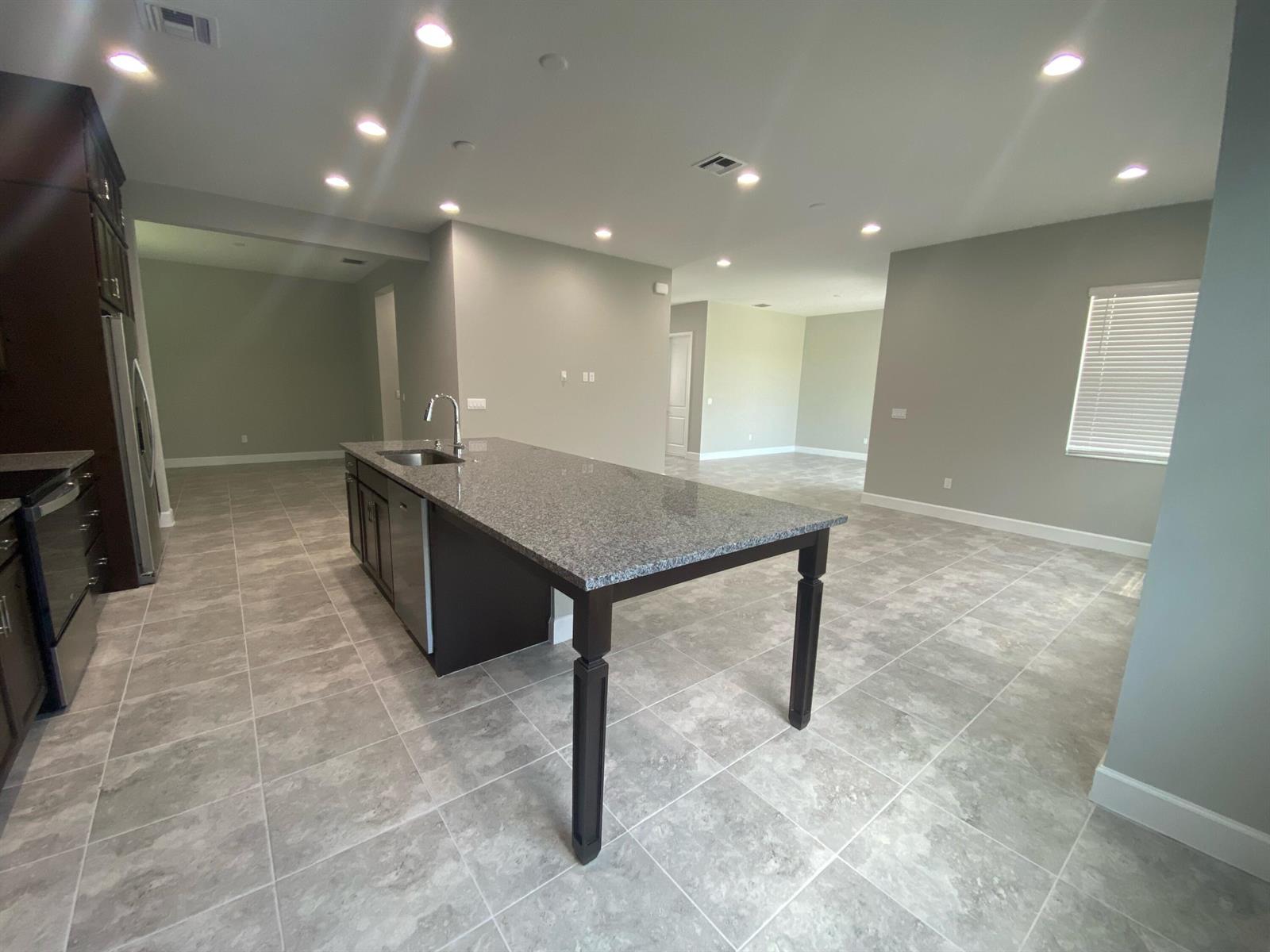 A kitchen island with a granite countertop and dark cabinets sits on a tiled floor — 5383 Pecan Drive, Westlake FL 33470, WESTLAKE, FL