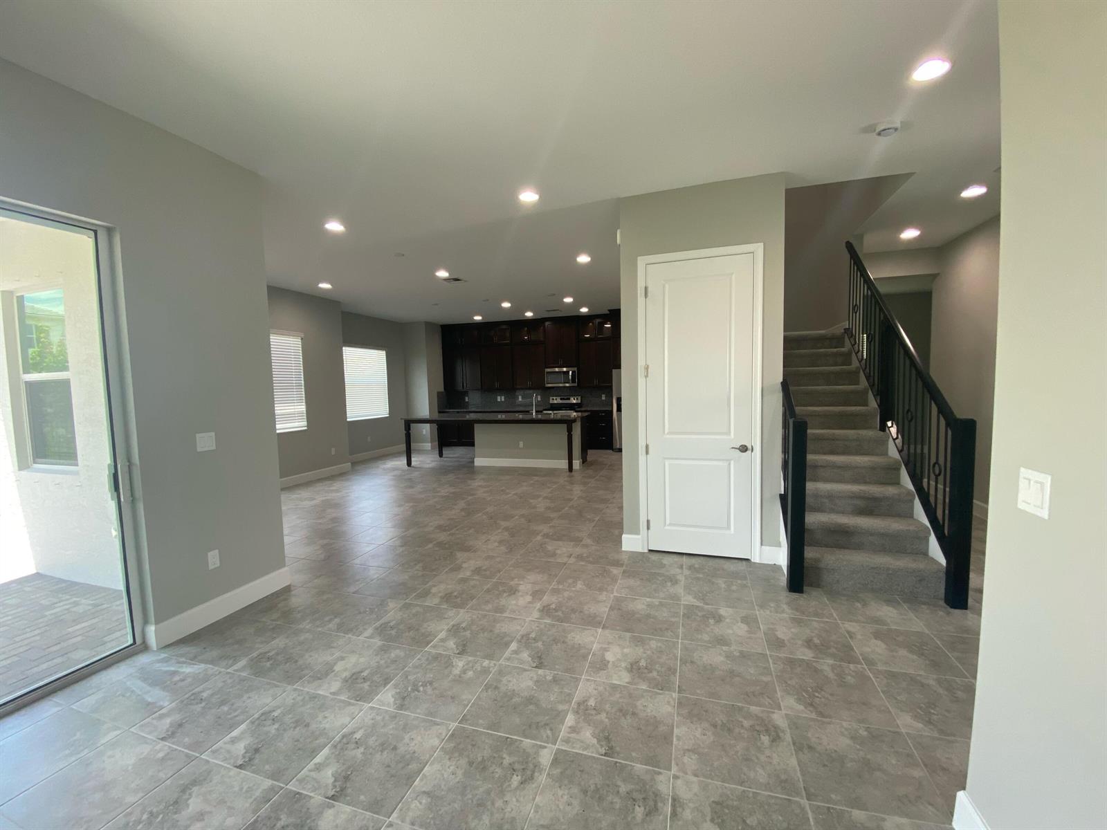 An open-concept living area features tile flooring, a kitchen with dark cabinetry, and a staircase — 5383 Pecan Drive, Westlake FL 33470, WESTLAKE, FL