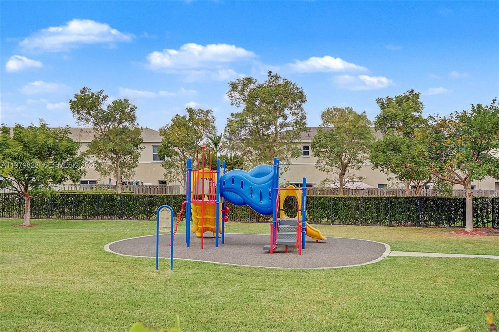 A colorful playground structure sits on a rubberized surface in a grassy residential backyard — 445 NE 4th St, Florida City FL 33034, FLORIDA CITY, FL