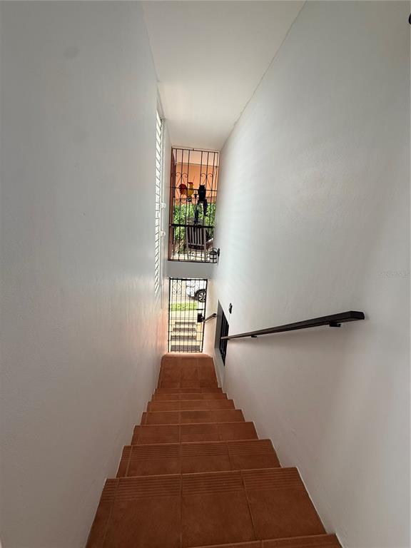 A staircase with brown tile steps leads down toward a metal security gate and door — Q24 Calle 12 CALLE ANTONIA SÁEZ, URB BORINQUEN, CABO ROJO, PR