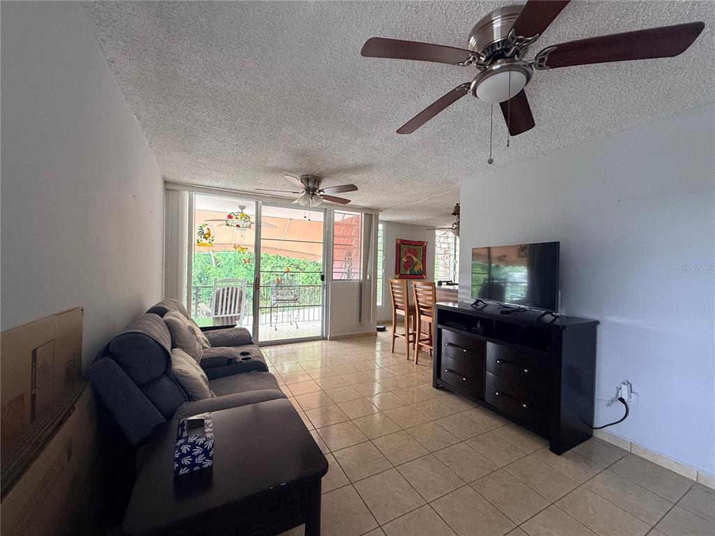 A living room features tile flooring, a ceiling fan, a sofa, and a television console — Q24 Calle 12 CALLE ANTONIA SÁEZ, URB BORINQUEN, CABO ROJO, PR