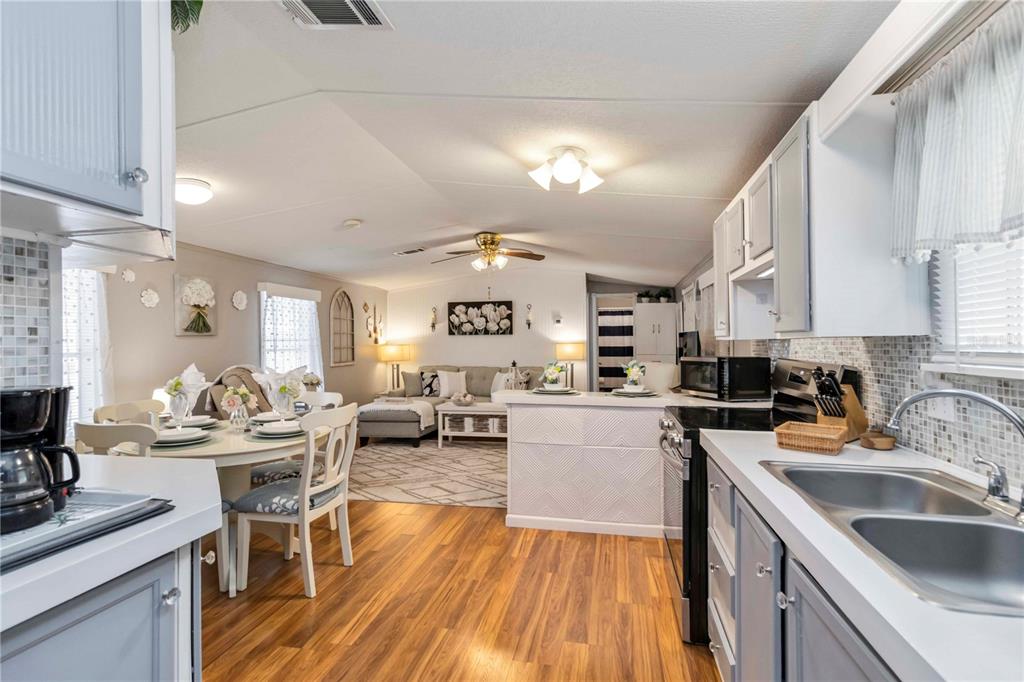 A kitchen with gray cabinets and a stainless sink opens to a dining and living area — 10303 BURNT STORE ROAD UNIT 230, PUNTA GORDA, FL