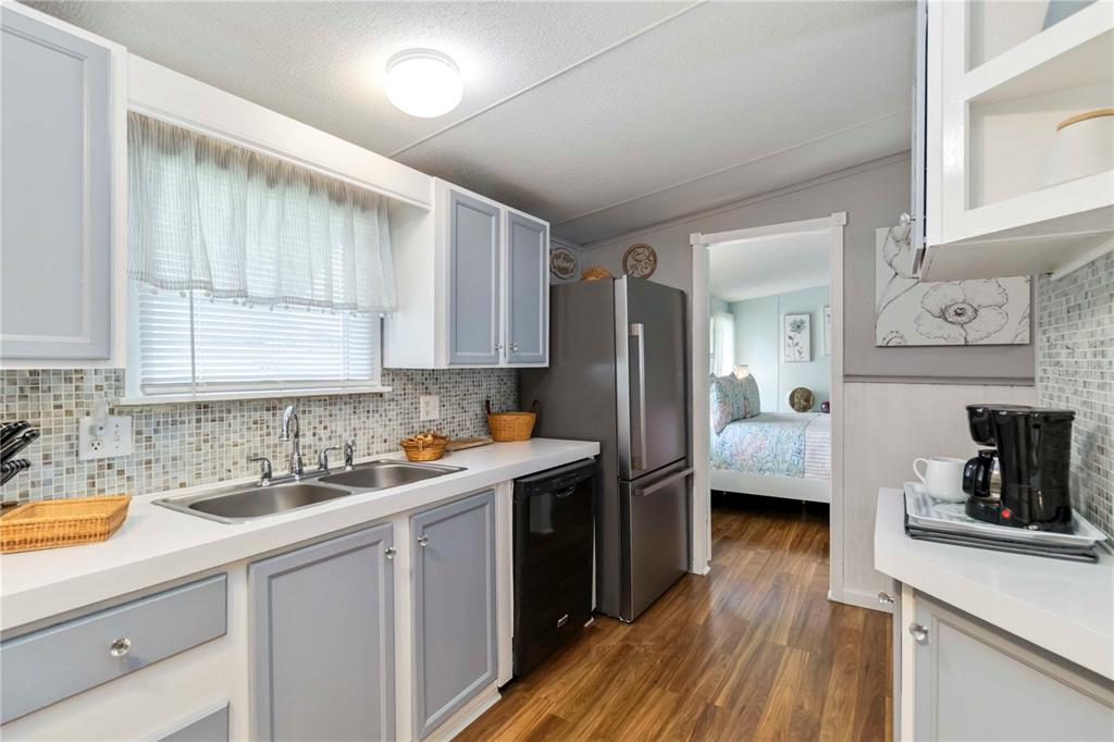 A kitchen features light blue cabinets, a stainless steel refrigerator, and a mosaic tile backsplash — 10303 BURNT STORE ROAD UNIT 230, PUNTA GORDA, FL