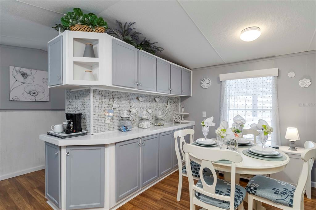 A kitchen and dining area features gray cabinets, a mosaic backsplash, and a round table — 10303 BURNT STORE ROAD UNIT 230, PUNTA GORDA, FL