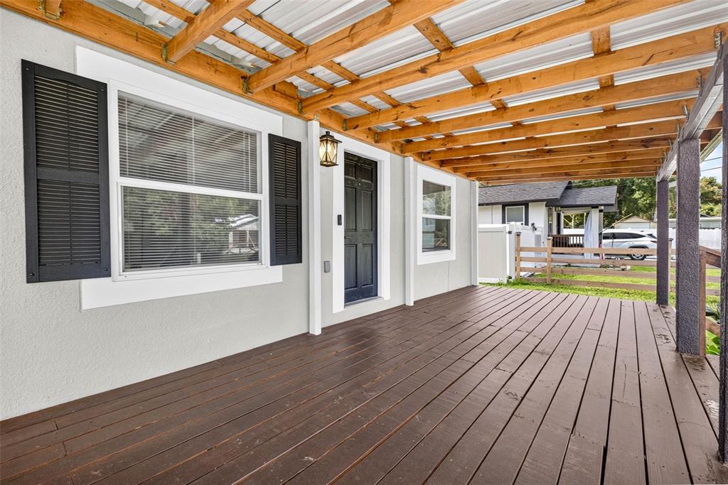 A covered wooden deck with a dark door and shuttered windows on a house exterior — 14352 LAWRENCE STREET, DADE CITY, FL