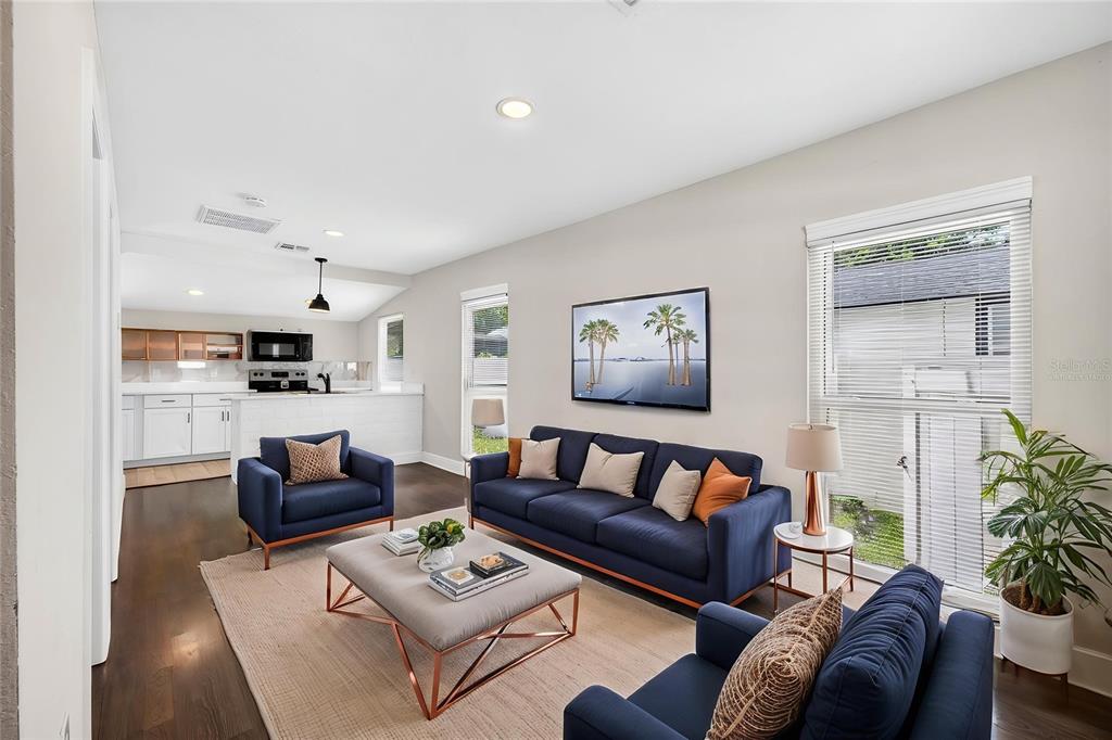 A living room features dark blue sofas, a light gray ottoman, and an open kitchen — 14352 LAWRENCE STREET, DADE CITY, FL