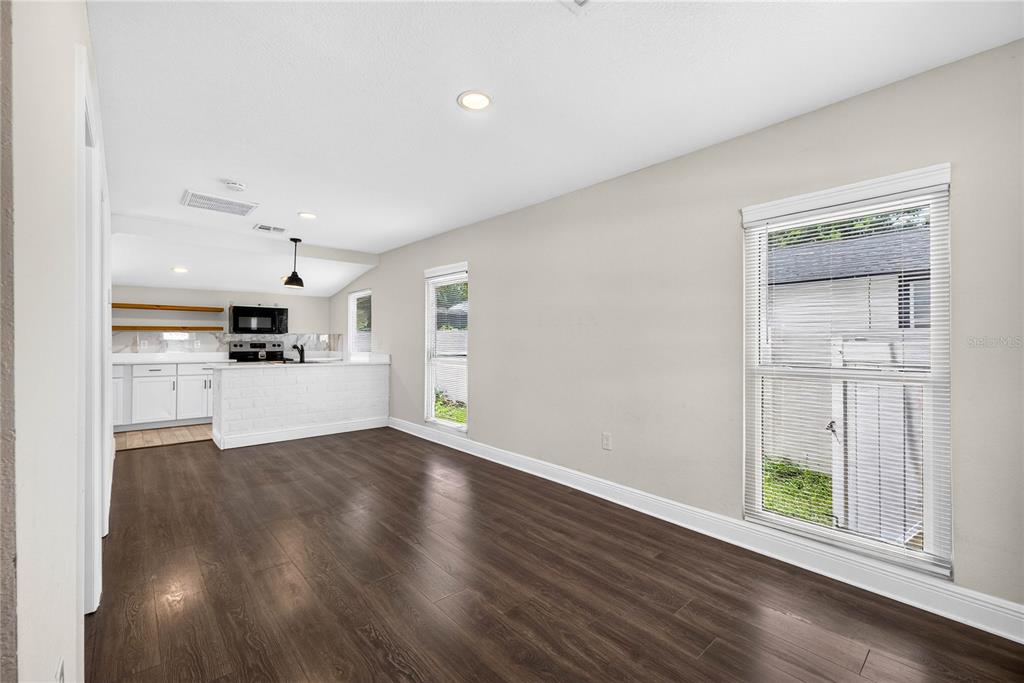 A dining area with dark wood-look flooring, white walls, and a view into the kitchen — 14352 LAWRENCE STREET, DADE CITY, FL