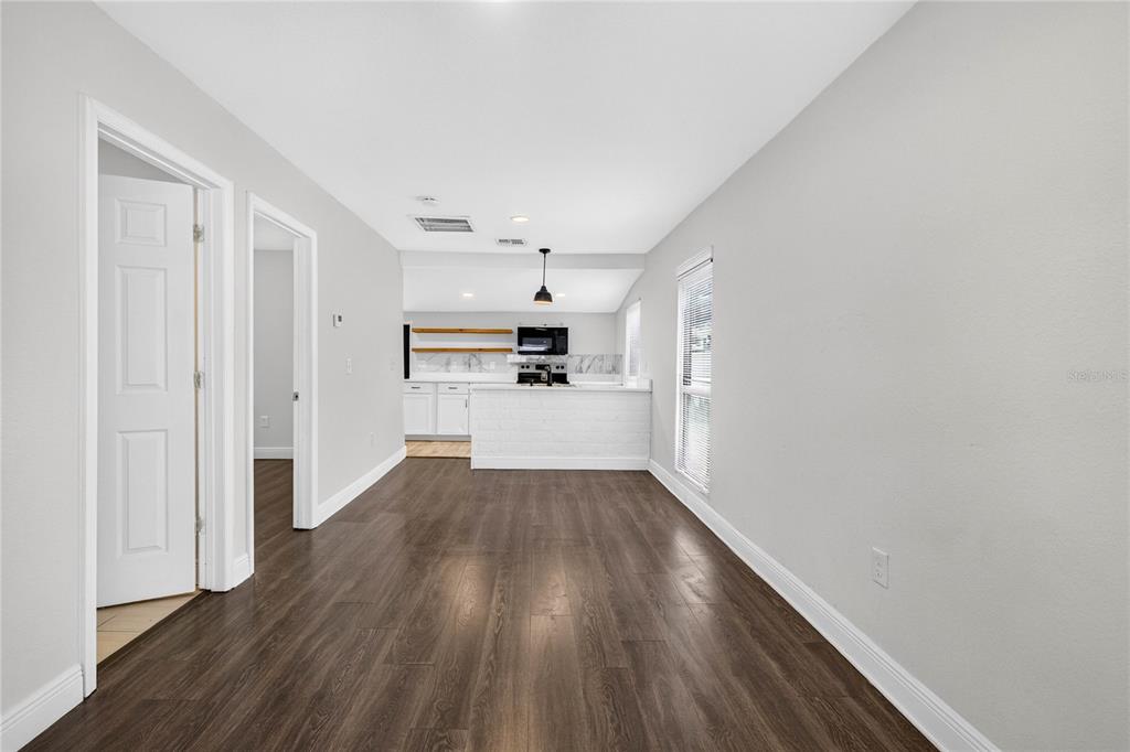 A living area with dark wood-look flooring leads to a kitchen with white cabinets — 14352 LAWRENCE STREET, DADE CITY, FL
