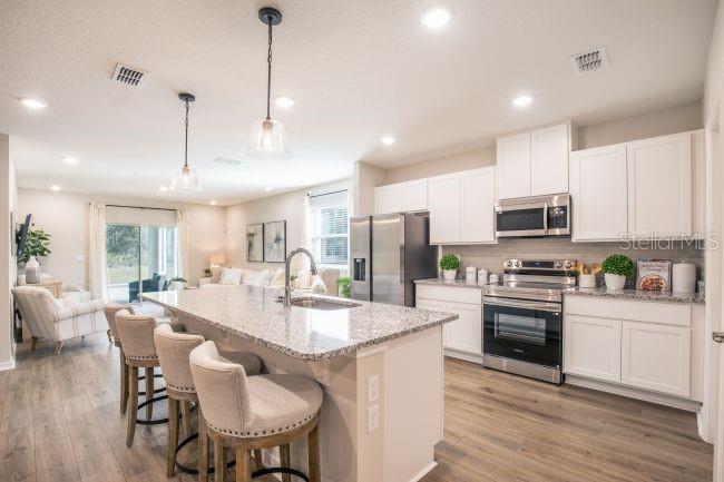 A kitchen with white cabinets, granite countertops, and an island with bar seating — 8 ROXBURY LANE, PALM COAST, FL