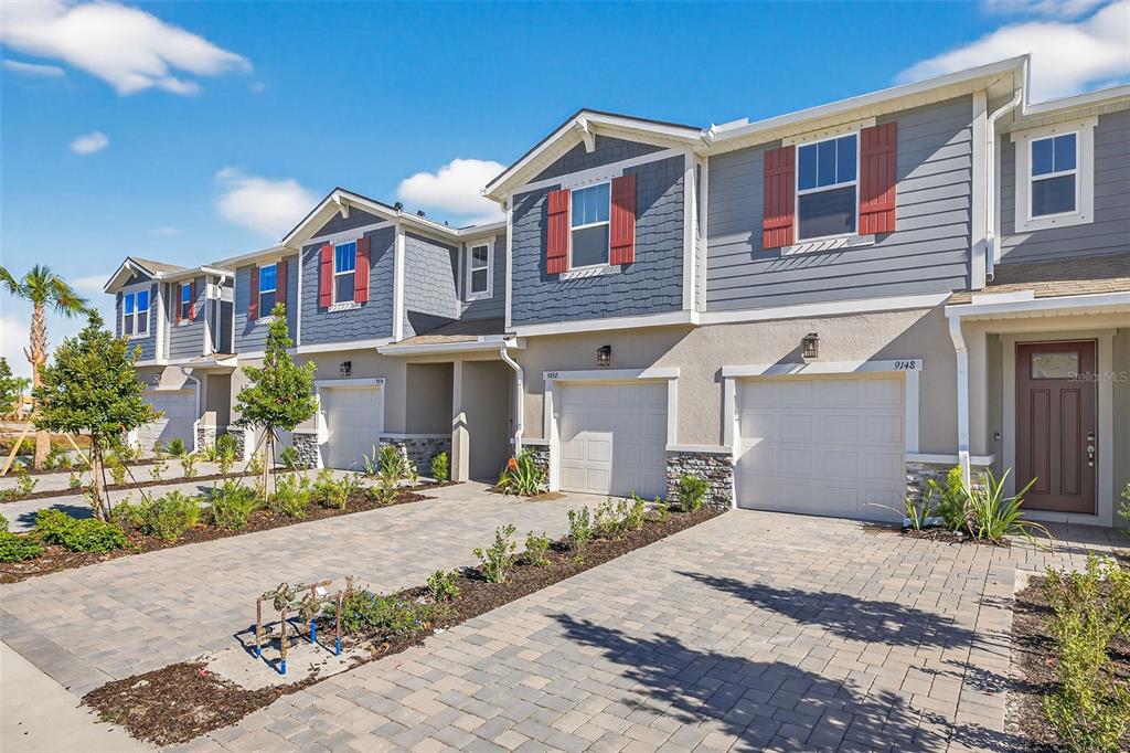A row of modern townhomes with gray siding, red shutters, and paved driveways — 9148 AURELIA AVENUE, PARRISH, FL