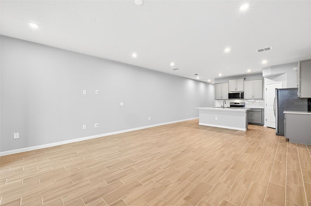An open-concept living area features light wood-look tile flooring, gray walls, and a modern kitchen — 9148 AURELIA AVENUE, PARRISH, FL