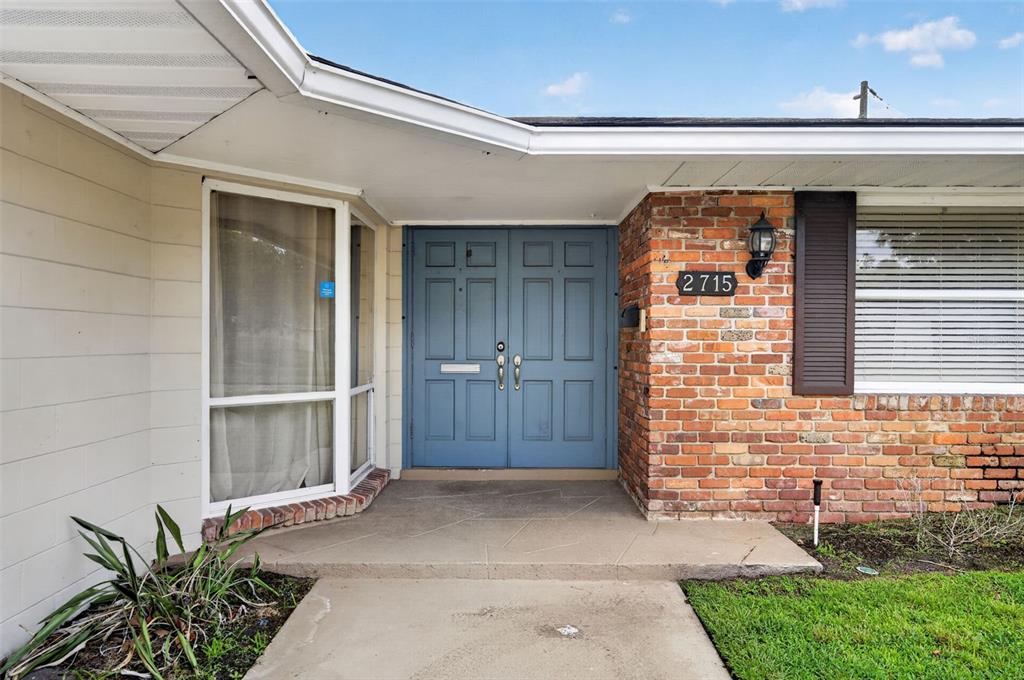 A house exterior features a blue double front door, brick siding, and a concrete porch — 2715 PRINCE JOHN ROAD, WINTER PARK, FL